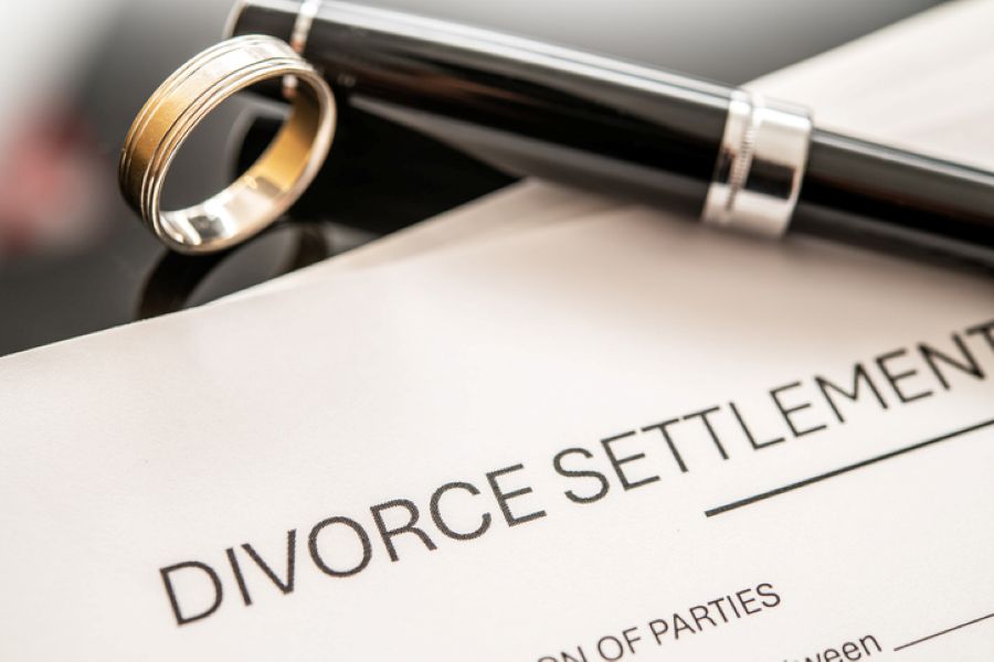 Divorce settlement document with wedding rings and pen