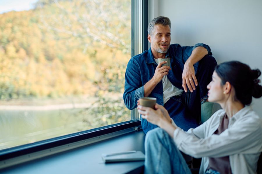 Thoughtful couple seated indoors having a calm, serious conversation by a window